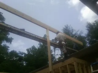 Carpenter setting a ridge beam over a new addition frame — Ice Dam Removal by Roofing Brothers in Cambridge