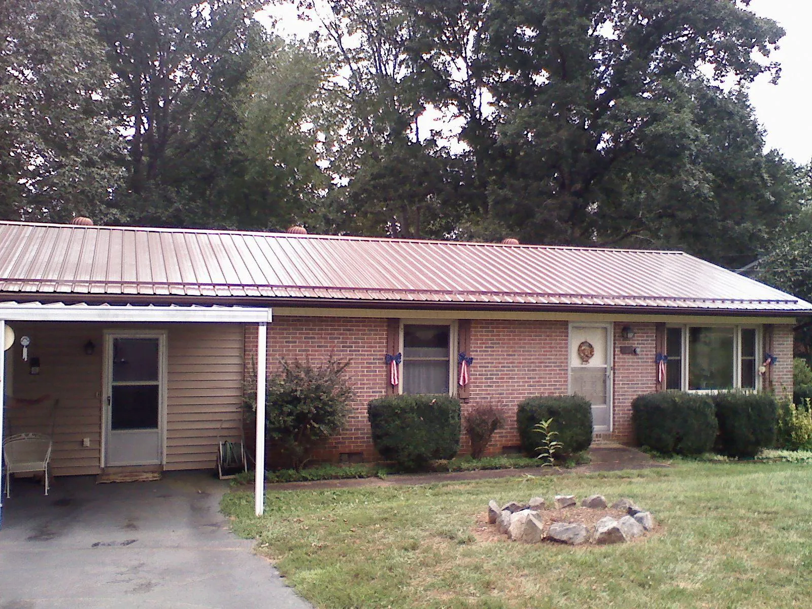 Bronze metal roof and carport on a brick ranch home — Roof Repair work by our crew in Cambridge